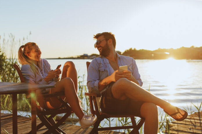 Couple-laughing-by-lake-with-phones.jpg